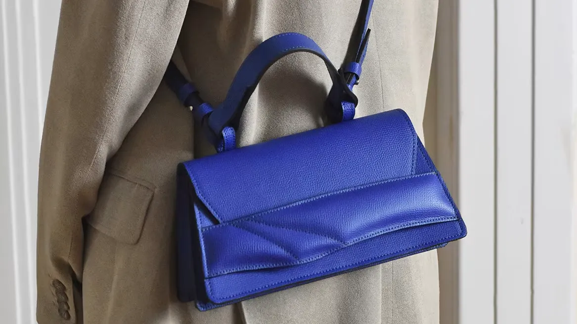 Geometric flap crossbody bag with crisp angular folds and architectural silhouette.