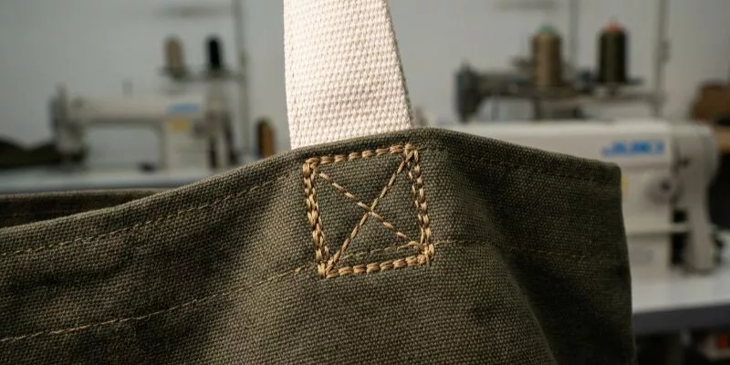 Close-up of a reinforced Box-X handle stitch on heavy canvas under load stress