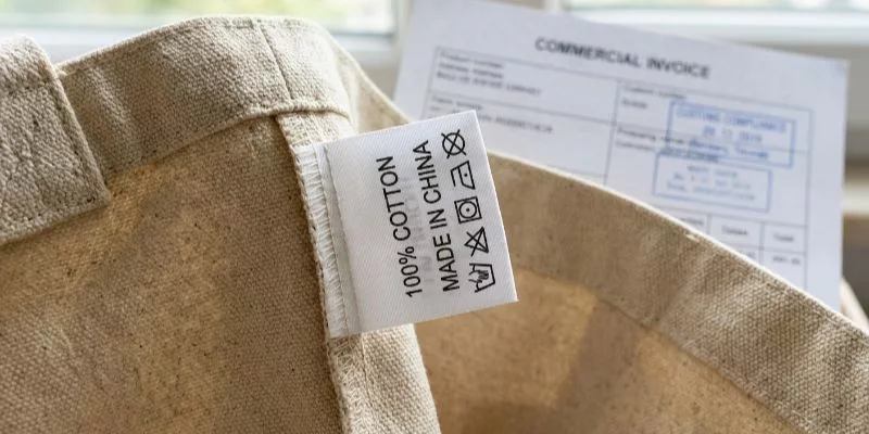 Sewn-in bag label showing fiber content next to customs compliance paperwork