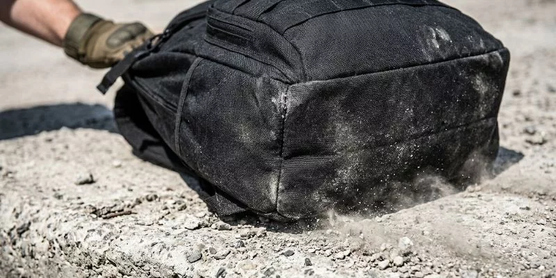Heavy-duty tactical backpack being dragged on rough concrete demonstrating high abrasion resistance