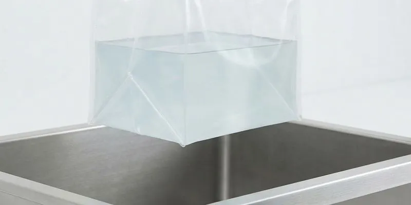 Water-filled clear PEVA pouch hanging over a sink during a leak test