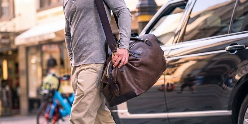Weekender duffle bag carried over the shoulder beside a car for short-haul travel