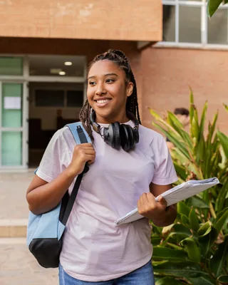 Student with backpack and books walking on campus