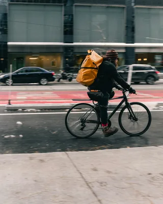 Cyclist with large yellow backpack riding on city street