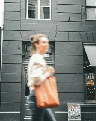 Woman walking down street carrying a brown bag