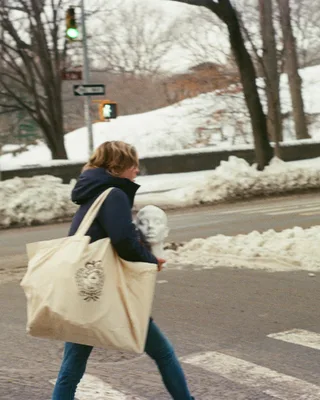 Woman with large tote bag crossing snowy street